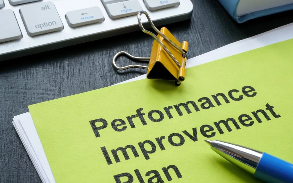 A performance improvement plan document with a binder clip and pen