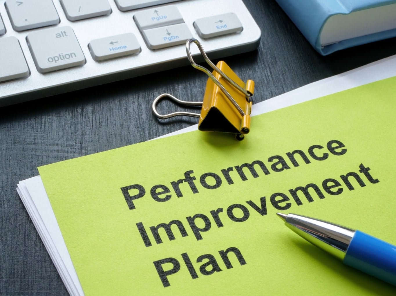 A performance improvement plan document with a binder clip and pen
