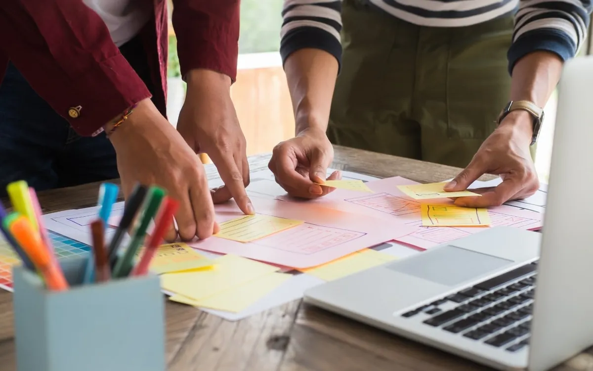 Two people sketching ideas and plans on sticky notes at a table