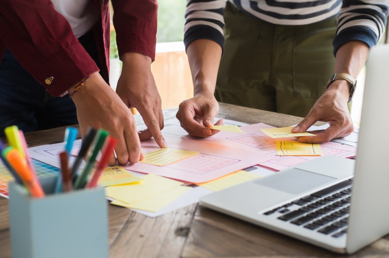 Two people sketching ideas and plans on sticky notes at a table